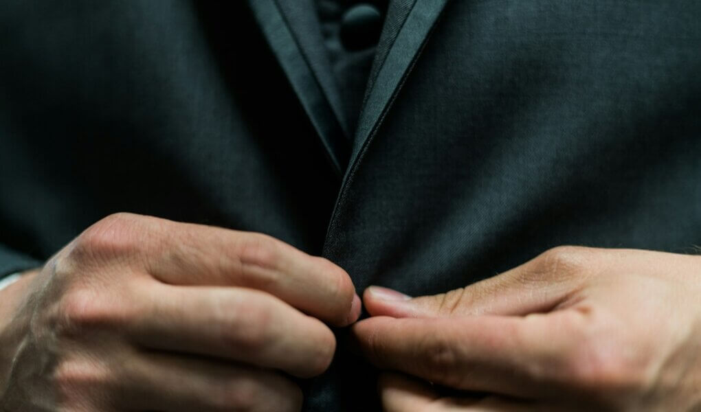 person holding black suit jacket button