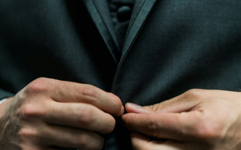 person holding black suit jacket button