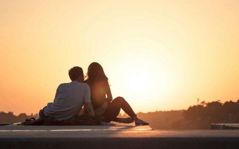 couple sitting near trees during golden hour