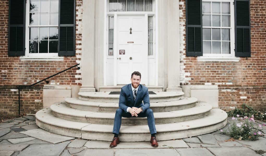 man in blue suit sitting on brown concrete stairs