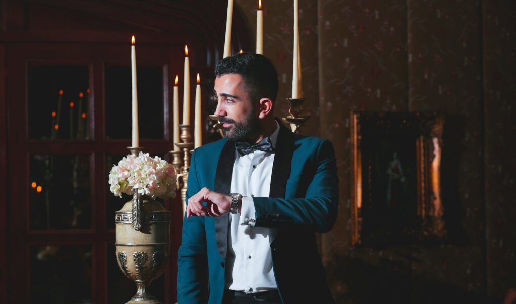 man in black suit jacket holding candle stick