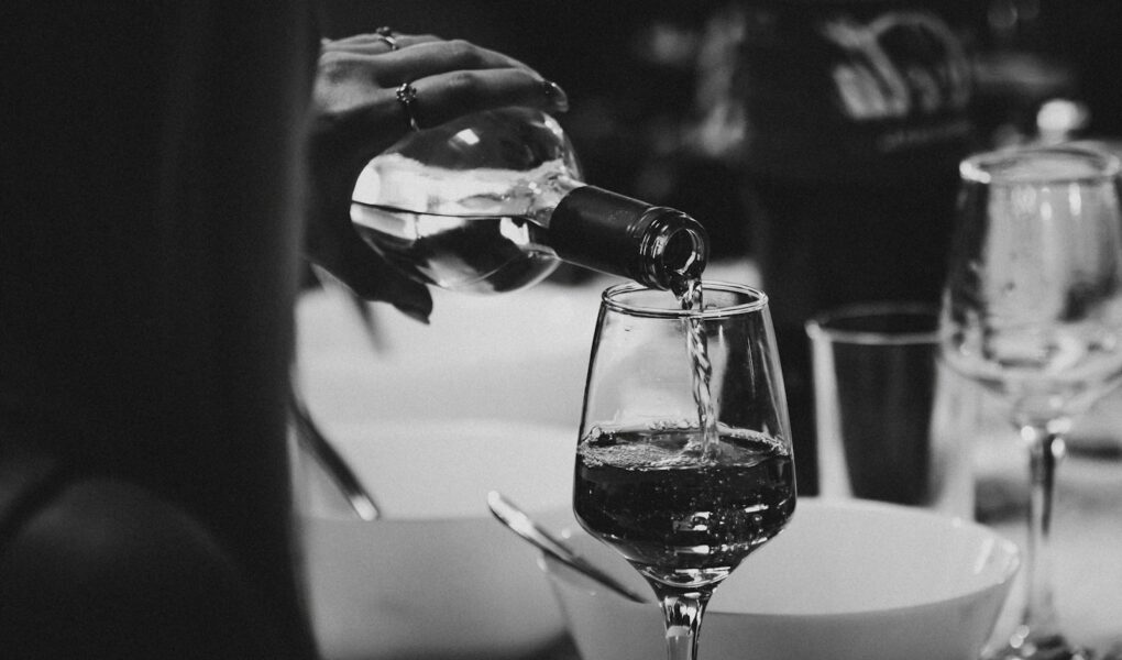 a person pouring wine into a wine glass