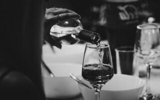 a person pouring wine into a wine glass